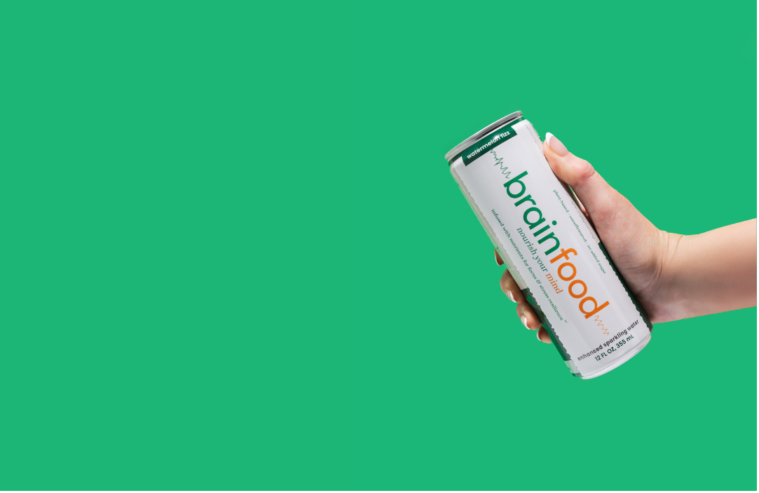 Hand holding a can of BrainFuel against a green background